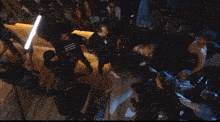 a crowd of people are gathered in a dark room and one of them is wearing a shirt that says zeusz
