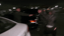 a group of people standing around a white car with a license plate that starts with the letter s