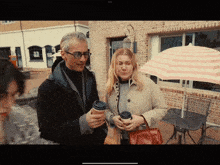 a man and a woman are standing under an umbrella in front of a building