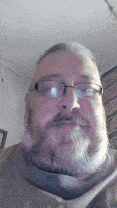 a man with a beard wearing glasses and a grey shirt