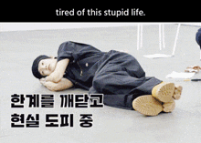 a man is laying on the floor with the words tired of this stupid life above him