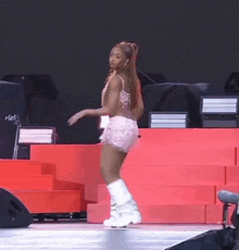 a woman is dancing on a stage wearing shorts and boots .
