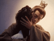 a man with a crown on his head is kissing a woman on the forehead