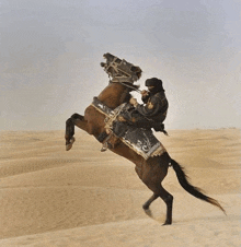 a man riding a horse in the desert with a black and gold saddle