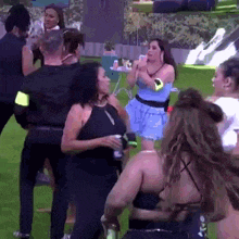 a group of women are dancing in a field while a man stands in the background .