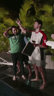 a man in a green shirt is standing next to a man in a white shirt with the letter e on it