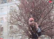 a woman in a pink hat and scarf is walking in a park