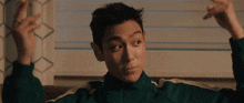 a man in a green jacket sits on a bed