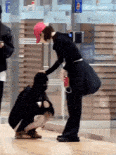 a woman wearing a red hat is petting another woman 's head