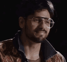 a close up of a man wearing glasses and a denim jacket .