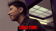 a man in a black jacket is smiling with the words chili time behind him