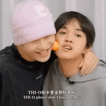 a man wearing a pink supreme hat kisses another man