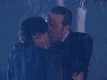 a man and a woman kissing in the rain .