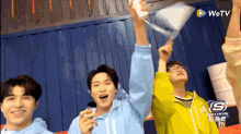 a group of young men are holding up their arms in the air in front of a wetv logo