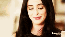 a woman with long black hair is smiling with her eyes closed and wearing a black shirt .