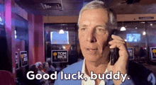a man is talking on a cell phone and says good luck buddy .