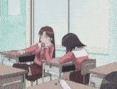 two girls are sitting at desks in a classroom . one of the girls is wearing glasses .