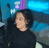 a woman is sitting in front of a neon sign that says hustle