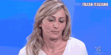 a woman wearing a white shirt and a microphone on a blue background with trash italiano written above her .