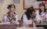 a group of girls are sitting at desks in a classroom with the words free fire x on the bottom right
