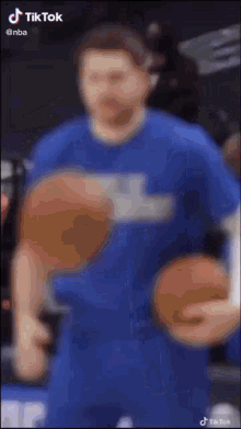 a man in a blue shirt is holding a basketball in his hand .