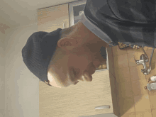 a man wearing a black beanie looks down at something