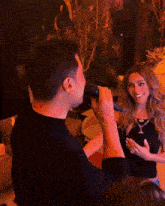 a man is singing into a microphone while a woman smiles behind him