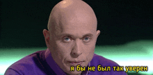 a bald man wearing a purple shirt with a caption in a foreign language