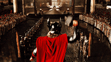 a man in a red cape is holding a hammer in front of a large crowd