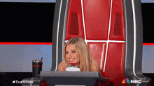 a woman is sitting in a chair with a nbc logo on the back