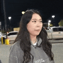 a woman with long hair is wearing a gray hoodie and a microphone .