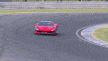 a red sports car driving on a track with grass in the background