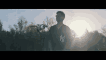 a man wearing a ny jersey is standing in front of trees