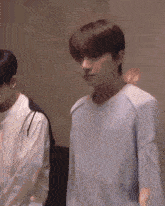 a man wearing a light blue sweater is standing next to another man
