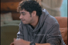 a man with curly hair is wearing a grey hoodie with the hashtag marthony14