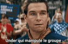 a man standing in front of a crowd with the words under qui manipule le groupe on his face