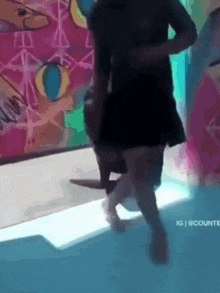 a man and a woman are dancing in front of a wall with graffiti