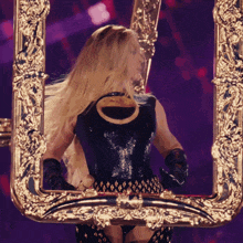 a woman in a black dress is standing in front of a gold picture frame