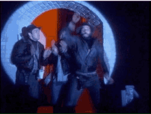 two men in cowboy hats are standing in a tunnel with their arms in the air