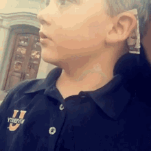 a young boy wearing a black shirt with the letter u on the front