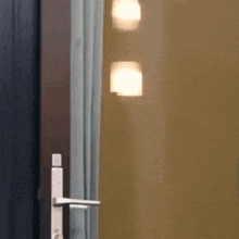 a woman is peeking out from behind a curtain and looking at the camera .