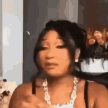 a woman is making a funny face while wearing a necklace and a black tank top .