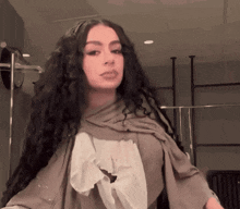 a woman with long curly hair and a scarf around her neck