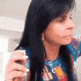 a woman with long black hair is brushing her hair while wearing a blue shirt .