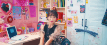 a girl is sitting at a desk in a room with a laptop on it