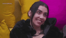 a woman is smiling while sitting on a couch with yellow pillows .