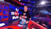 a man wearing a t-shirt that says u stop me is walking through a wrestling ring .