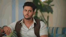 a man with a beard sits on a couch with his hand on his knee