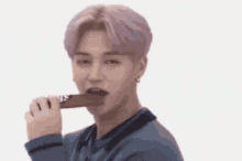a man with pink hair is eating a chocolate bar .