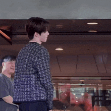 a man in a plaid jacket is standing next to another man in a black shirt